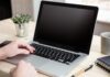 Computer laptop with black blank screen on a wooden desk